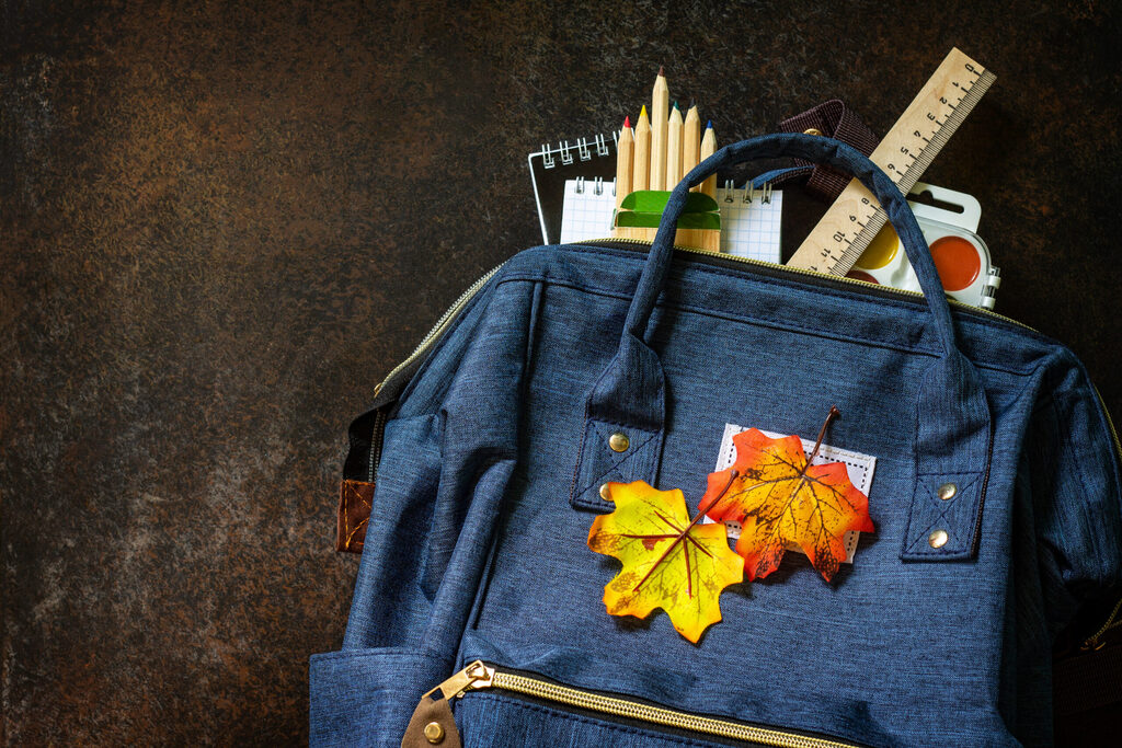 Una mochila abierta con lápices, cuaderno, regla y acuarelas